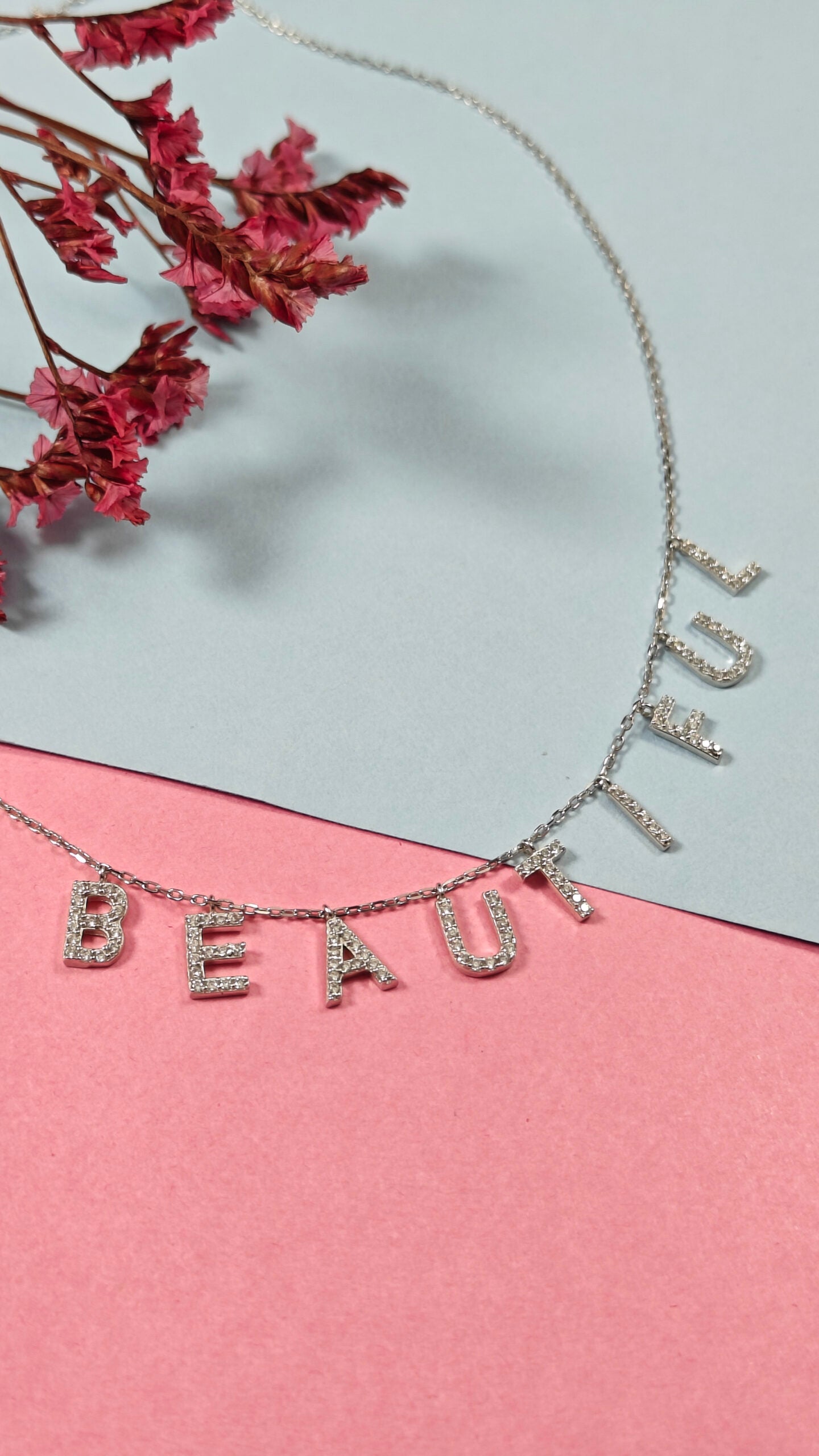 Necklace with 'BEAUTIFUL' letters on a pink and gray background